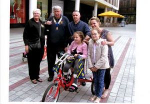 the Dunn family being presented with the special tricycle donated to by Exeter West Club, by Lion Preident Mike and Lion Caril